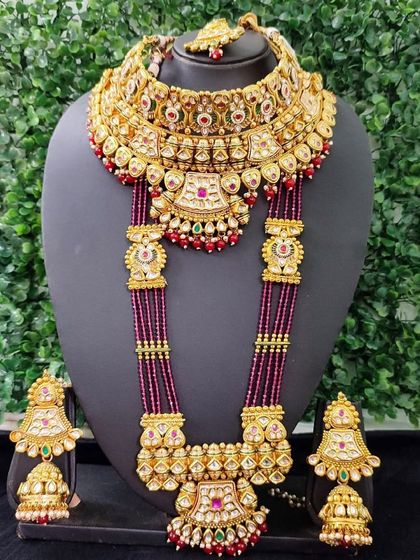 Own a piece of royalty with this bridal set featuring deep magenta beads. This exclusive sale item includes a choker, a long necklace, and jhumkas, blending traditional design with rich color.
