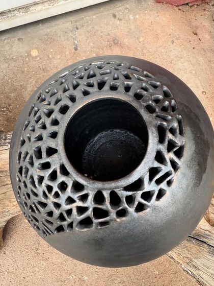 This wheel-thrown stoneware sphere features an intricate, hand-carved geometric pattern. I added a touch of gold to the metallic glaze to highlight the cuts and create a sense of depth.