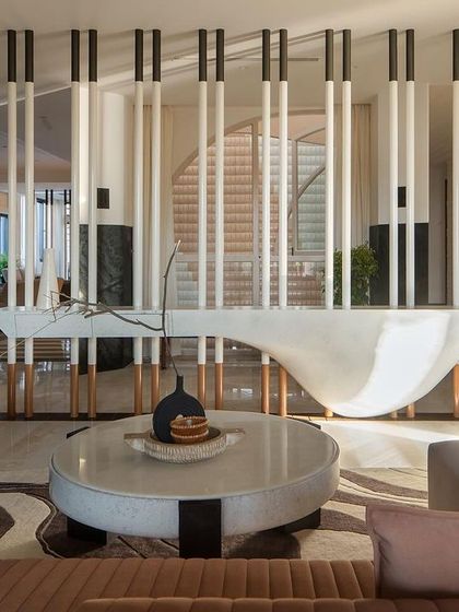 On the first floor, the living room transforms structural elements into sculptural expressions. The interplay of vertical lines and organic curves creates a harmonious and dynamic interior.