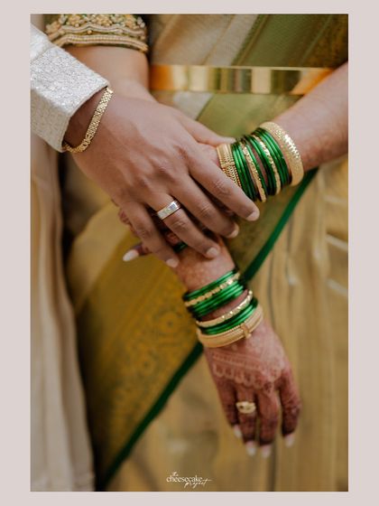 A detail shot of their hands, showing the bride's green bangles and the groom's ring.