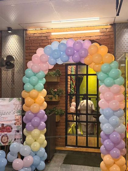 The entrance to the jungle-themed first birthday, featuring a pastel balloon arch and a personalized welcome sign on an easel.