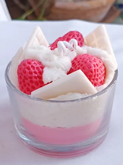 The strawberry ice cream candle, presented on a white surface to emphasize its colors.
