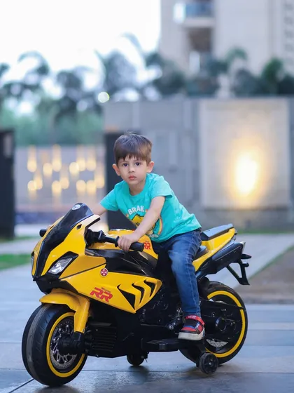 An outdoor shot of a boy looking cool and confident on a yellow toy motorcycle. Perfect for capturing a child's adventurous spirit.