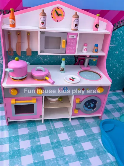 Our pink wooden pretend play kitchen, featuring a microwave, oven, sink, and a variety of pots, pans, and play food for little chefs.