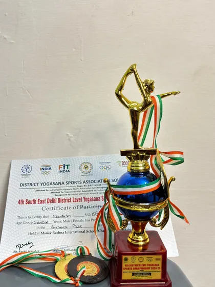 A close-up of the trophy, medals, and certificate from the District Level Yogasana Championship.
