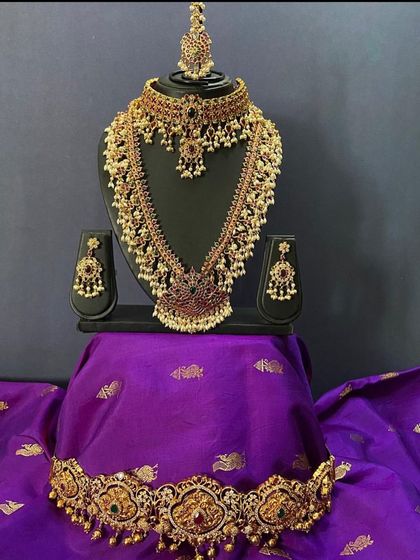 A beautiful guttapusalu set displayed on a traditional purple silk cloth to give you an idea of how it pairs with rich colours. This set includes a choker, long necklace, and vaddanam.