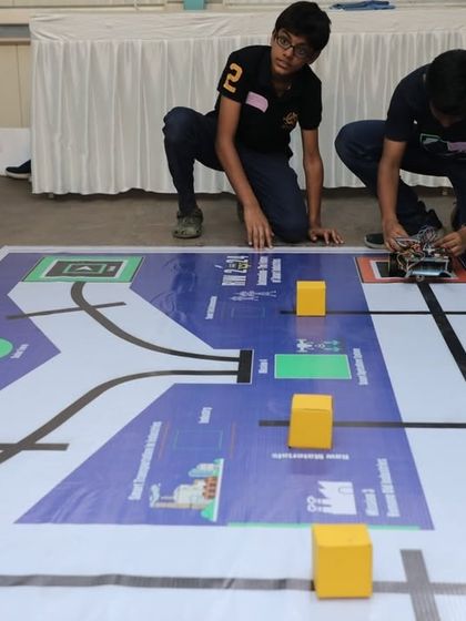 A student fine-tunes his Pick-and-Place Line Follower Robot. This robot is programmed to follow a designated path and use an arm to move objects, demonstrating skills in automation and precision control.