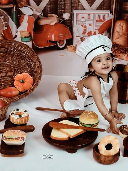 This little chef is looking up with a curious expression, surrounded by a feast of toy food. We create detailed and interactive sets to spark your child's imagination.