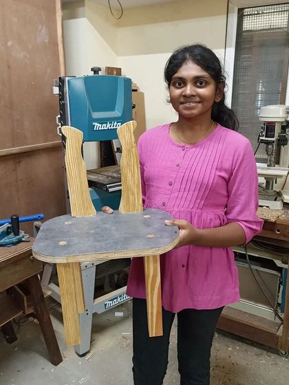 A student with the unique chair she designed, featuring curved back legs. This was made in a one-day experiential workshop for design students.