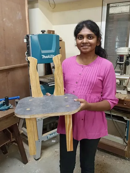 A student with the unique chair she designed, featuring curved back legs. This was made in a one-day experiential workshop for design students.