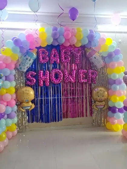 A pastel-colored balloon arch for a baby shower. The decoration includes "It's a Boy" and "It's a Girl" foil balloons on pillars, along with baby-themed foil balloons, keeping the gender a surprise.