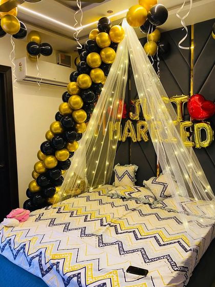 This view captures the full bed setup, including the "Just Married" foil balloons, the light canopy, and the balloon arch, creating a luxurious look for the newlyweds.