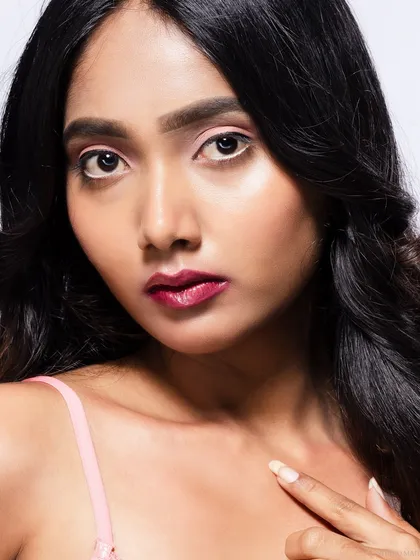 A close-up beauty portrait with a focus on a natural, glowing makeup look. The model's expression is soft and engaging.