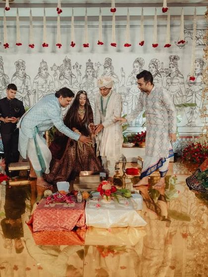 The wedding ceremony in progress. The mandap's design, with its blend of traditional brass, antique treasures, and a modern, hand drawn backdrop, created a setting that was both grand and deeply personal.