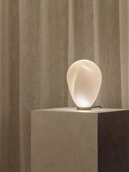 The white glass Solace lamp, with its soft, luminous glow, is shown here as a beautiful, sculptural object.