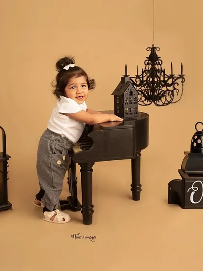 Making her own music. This toddler is fully engaged with the miniature piano, a perfect prop for capturing their curiosity and playful spirit in the studio.