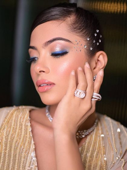 Blue vibes for a cocktail look. This pop of color on the eye, combined with face gems, creates a fun, glamorous, and modern party look.