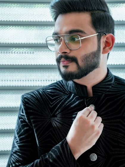 A close-up of the groom's engagement look. The black velvet jacket with a geometric pattern is a unique and stylish choice.