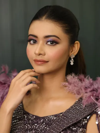 Get ready to turn heads with this captivating cocktail look. The purple smokey eye is the star of the show, paired with a sleek ponytail and a dramatic feathered outfit.