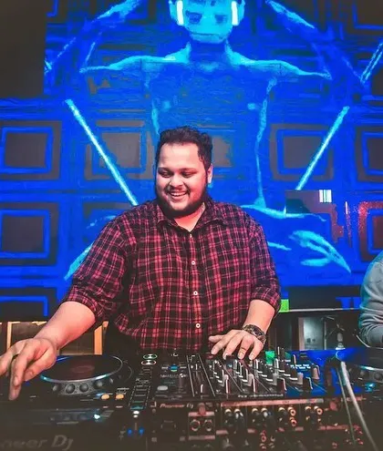A smiling shot of me behind the decks, with cool blue visuals in the background.