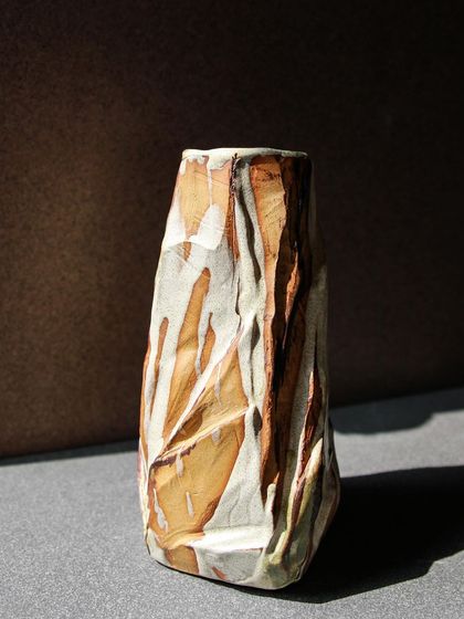 A tall, faceted Kurinuki vase, its surface resembling a cut down mountain, a result of my exploration into this sculptural hand building technique.