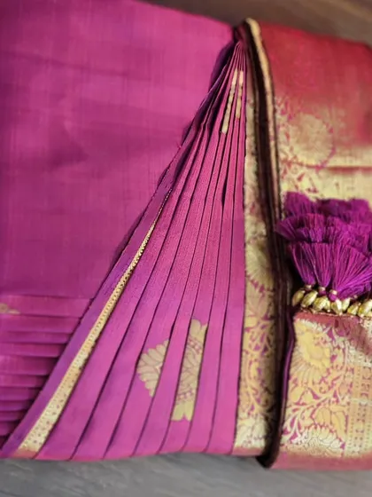 A beautiful magenta silk saree, box-folded with the decorative tassels displayed. It’s not just about convenience; it’s also about presenting the saree beautifully.