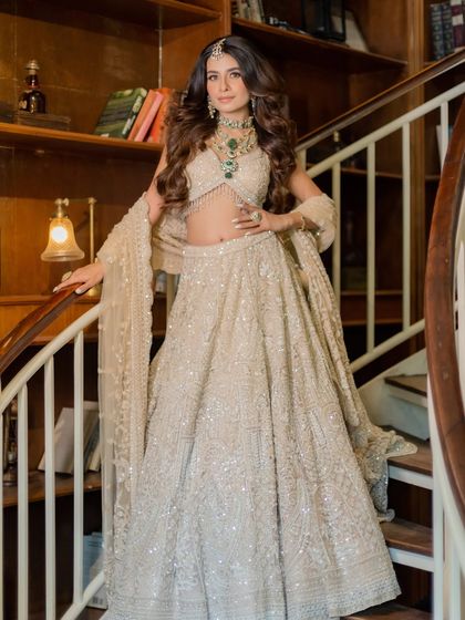 A full-length shot showcasing the grandeur of the ivory lehenga. The intricate all-over embroidery creates a stunning texture that is both luxurious and sophisticated.