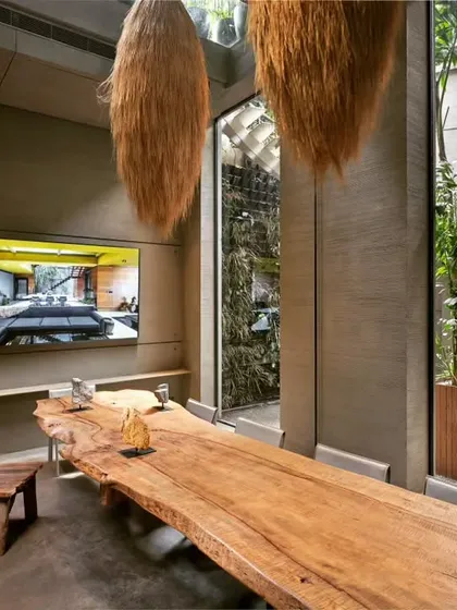 The main conference table is a single, massive slab of wood, serving as the anchor for our collaborative space. The textures of the hay-bale-inspired light fixtures and the living green wall visible through the glass create a rich, multi-sensory experience.
