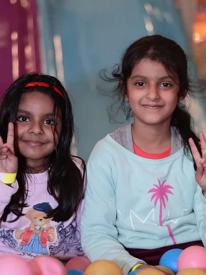 Two friends posing for a photo in the ball pit during our Christmas event. The playzone is a great place for kids to socialize and make new friends.