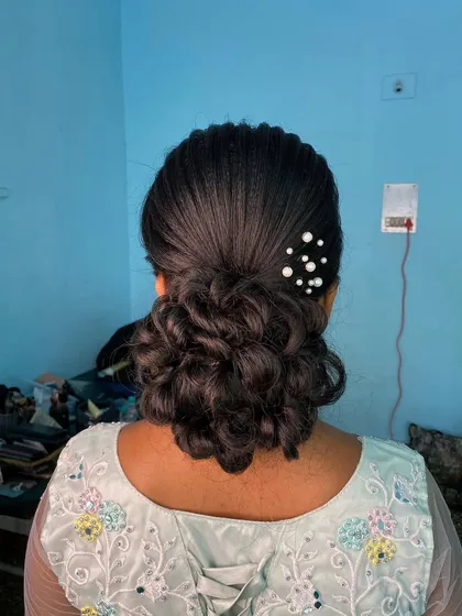 A 'welcome look' featuring a messy bun adorned with pearl accessories. This is a beautiful and elegant updo for a pre-wedding celebration.