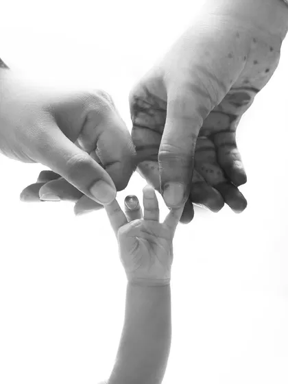 A tiny hand grasping a parent's finger, captured in beautiful black and white. This simple, powerful image tells a story of trust and love.