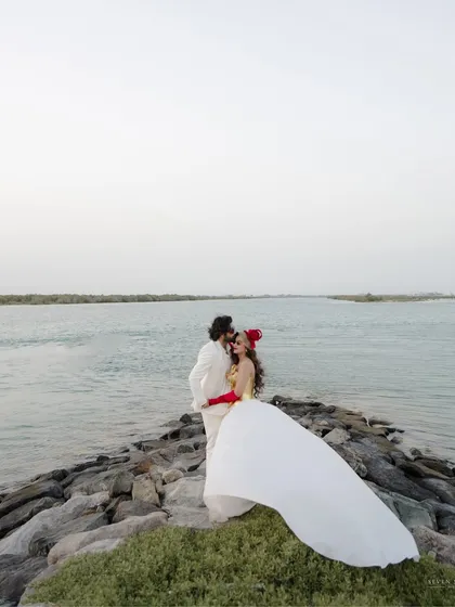 A bold and dramatic statement by the sea. The bride's flowing white dress against the dark rocks creates a powerful, high-fashion look for a coastal pre-wedding shoot.