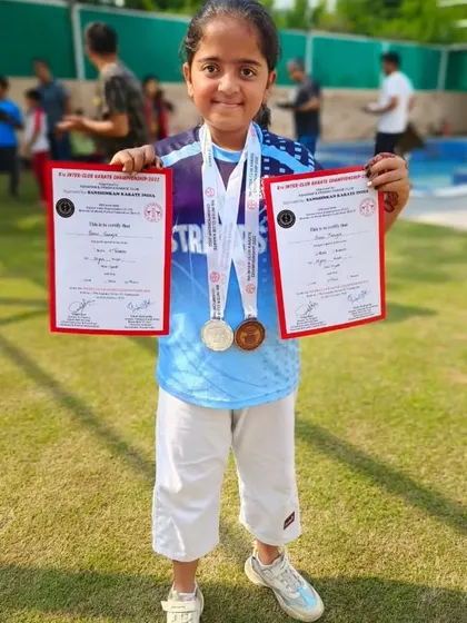 I am so proud of my students and their incredible performances. This young champion is holding her certificates and medals, a wonderful symbol of her achievement in the sport.