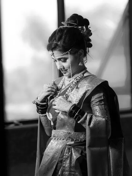 A timeless black and white photo of the bride adjusting her necklace, capturing a quiet, personal moment.