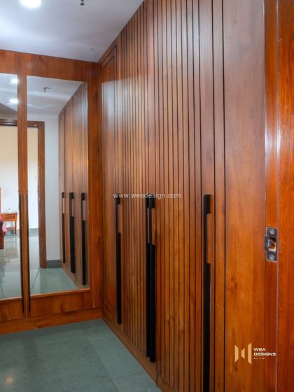 A walk-in wardrobe area with fluted veneer doors and a full-length mirror, showcasing our custom woodwork and attention to detail.