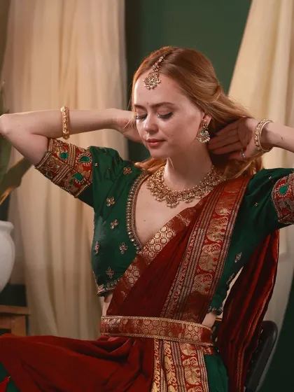 A candid-style shot of Irina Rudakova adjusting her hair, dressed in a traditional South Indian outfit, adding a natural and personal touch to the series.