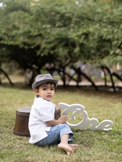 A candid shot of this little boy looking back, wearing a stylish hat for his outdoor first birthday shoot.