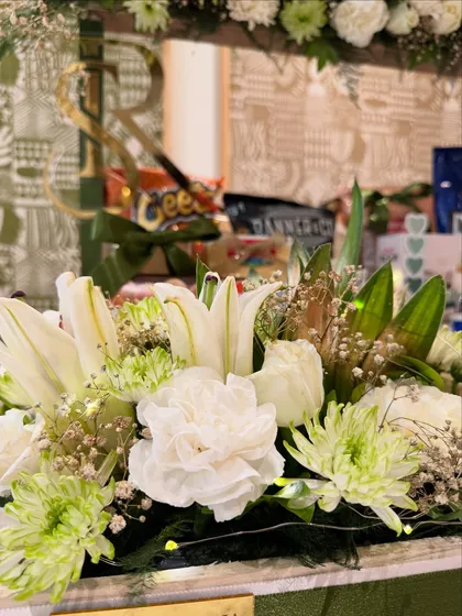 Fresh white lilies and carnations bring life and elegance to the arrangement, perfectly complementing the green and ivory theme of this grand Roka gift.