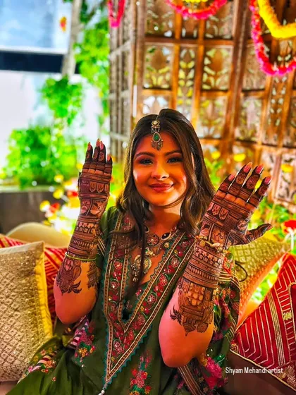 The bride proudly holds up her hands, showing off the detailed artwork that completes her festive look.
