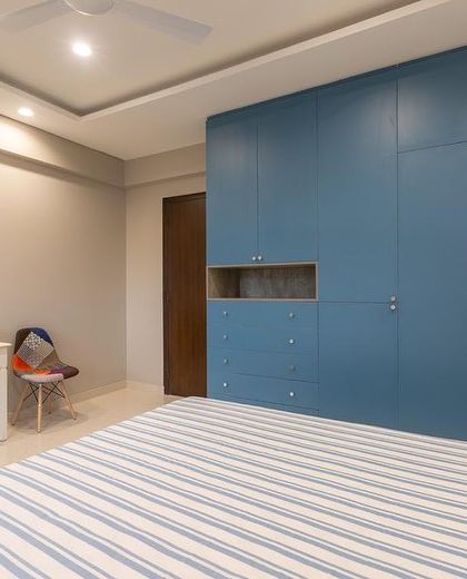 This guest bedroom uses a bold blue wardrobe to create a strong focal point. The room is designed to be multi-functional, doubling as a study.
