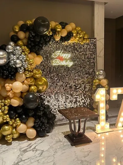 A chic 17th birthday celebration with a black, gold, and nude color scheme. The sequin wall, balloon arch, and light-up numbers create a sophisticated and modern party vibe.