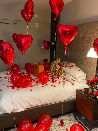 A simple and sweet romantic room setup. I use red heart-shaped foil balloons and rose petals scattered on the bed and floor to create a lovely surprise for your special someone.