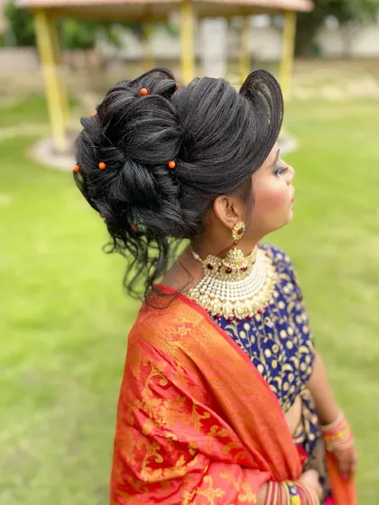 A high bun with intricate loops and soft tendrils. This modern and messy updo is a great option for a sangeet or cocktail party, offering a chic and stylish look.