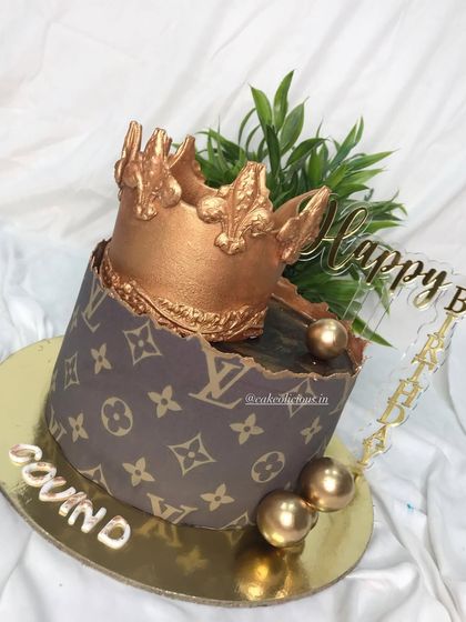 An LV themed crown cake for a stylish celebration. This ganache cake features the iconic LV print and a stunning edible gold crown on top.