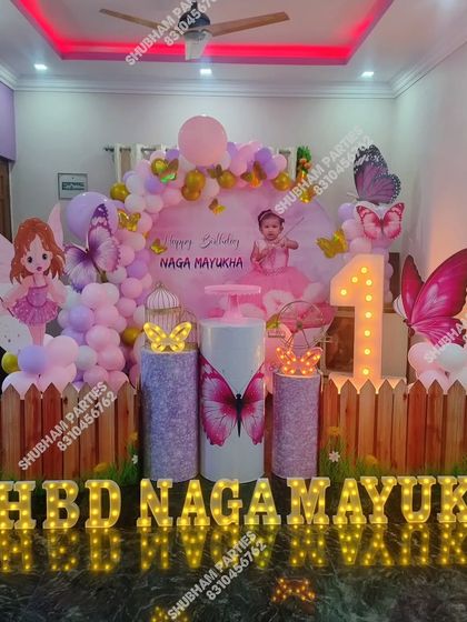 A fairy and butterfly themed birthday party with a picket fence, character cutouts, and large marquee letters.