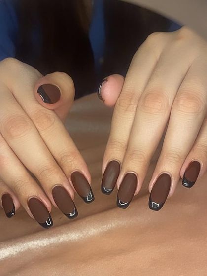 A matte brown French manicure with glossy black tips for a sophisticated, multi-textured look.