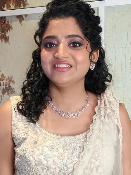 This bride's reception look is all about soft elegance. Her naturally curly hair is styled in a beautiful half-updo with a delicate accessory, and the makeup is kept soft and luminous.