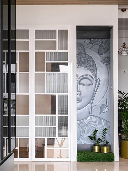 To create this serene niche, I modified the existing layout to build a dedicated space for this beautiful Buddha mural. The modern partition door next to it features a mix of frosted and fluted glass panels.