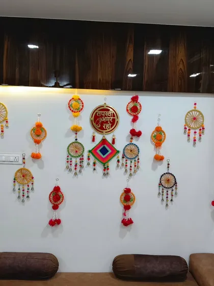 This is a closer look at the handmade wall decor I use for Tapasvi welcome ceremonies. The display includes colorful dream catchers, paper hangings, and the "Tapasvi Amar Raho" centerpiece, all arranged to bring a festive and personal feel to the living room.