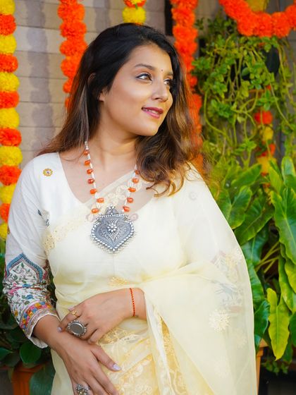 Another brand collaboration featuring a light yellow organza saree, styled with a statement silver pendant necklace with orange beads.